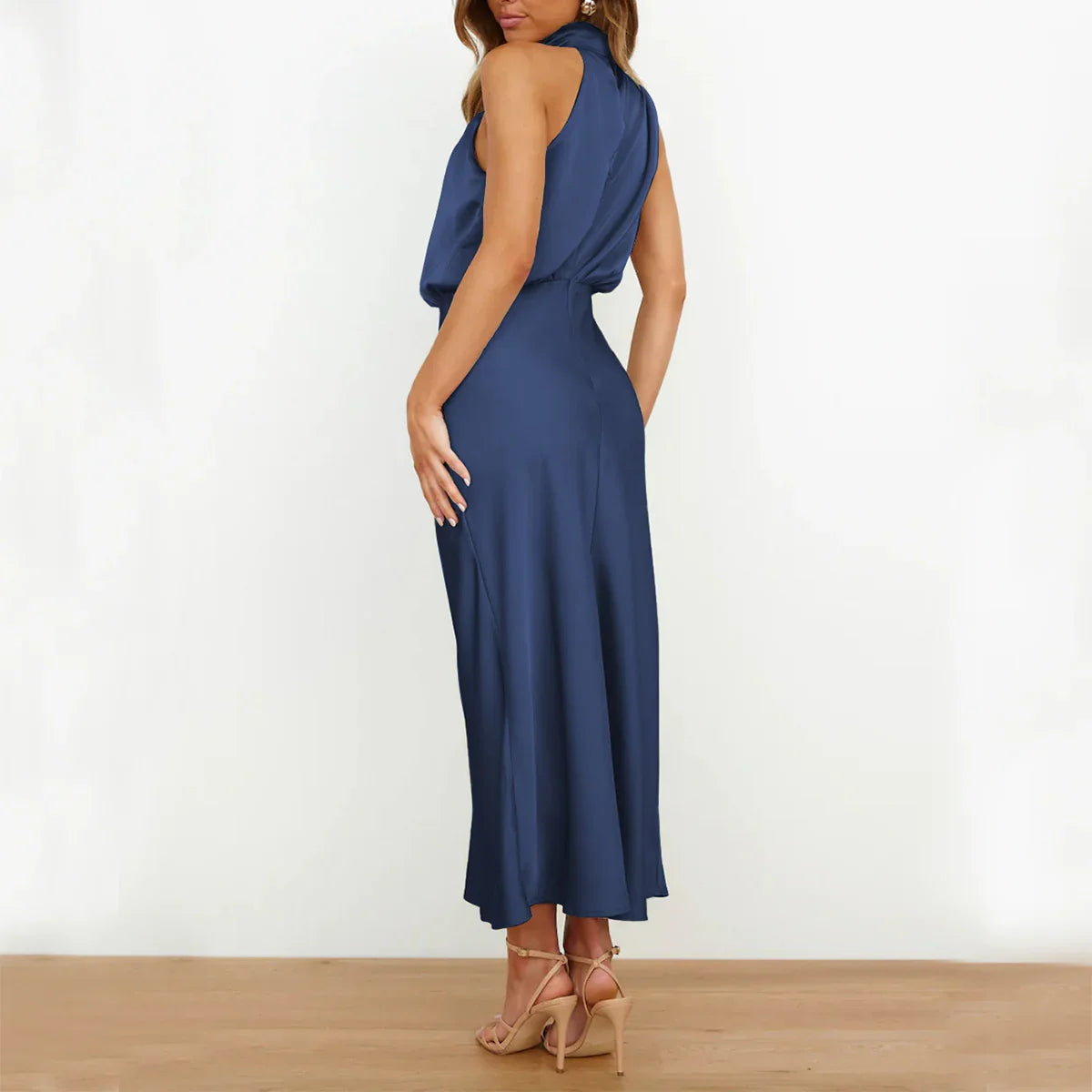 Woman wearing a sleeveless navy blue satin midi dress with a relaxed fit and open back.