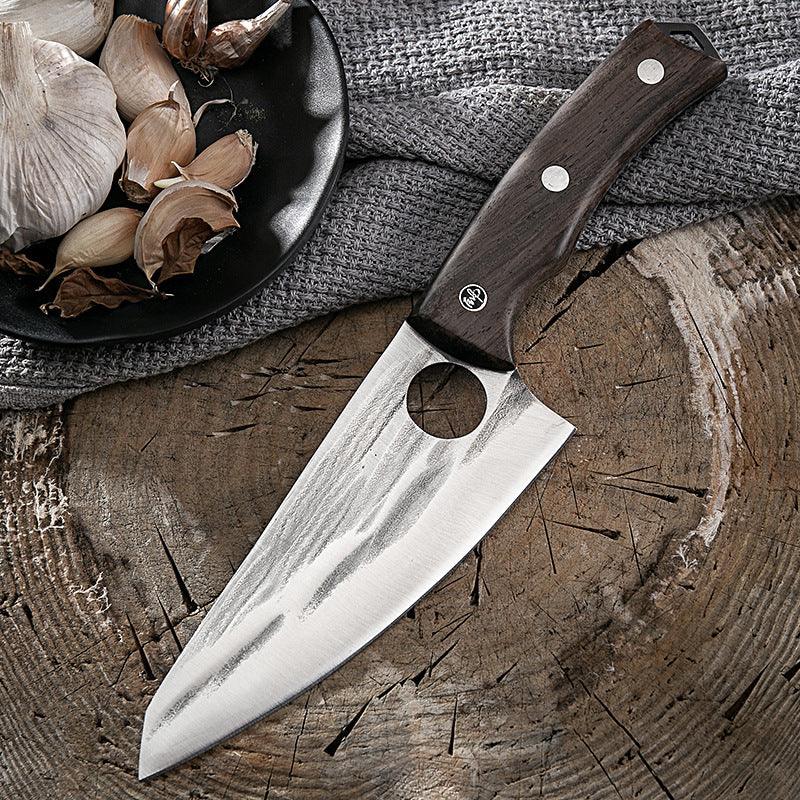 Stainless steel chef knife with dark wooden handle on rustic wood surface, next to garlic cloves