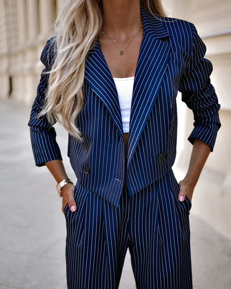 Woman wearing navy blue pinstripe suit with cropped blazer and wide-leg pants, white ribbed crop top.