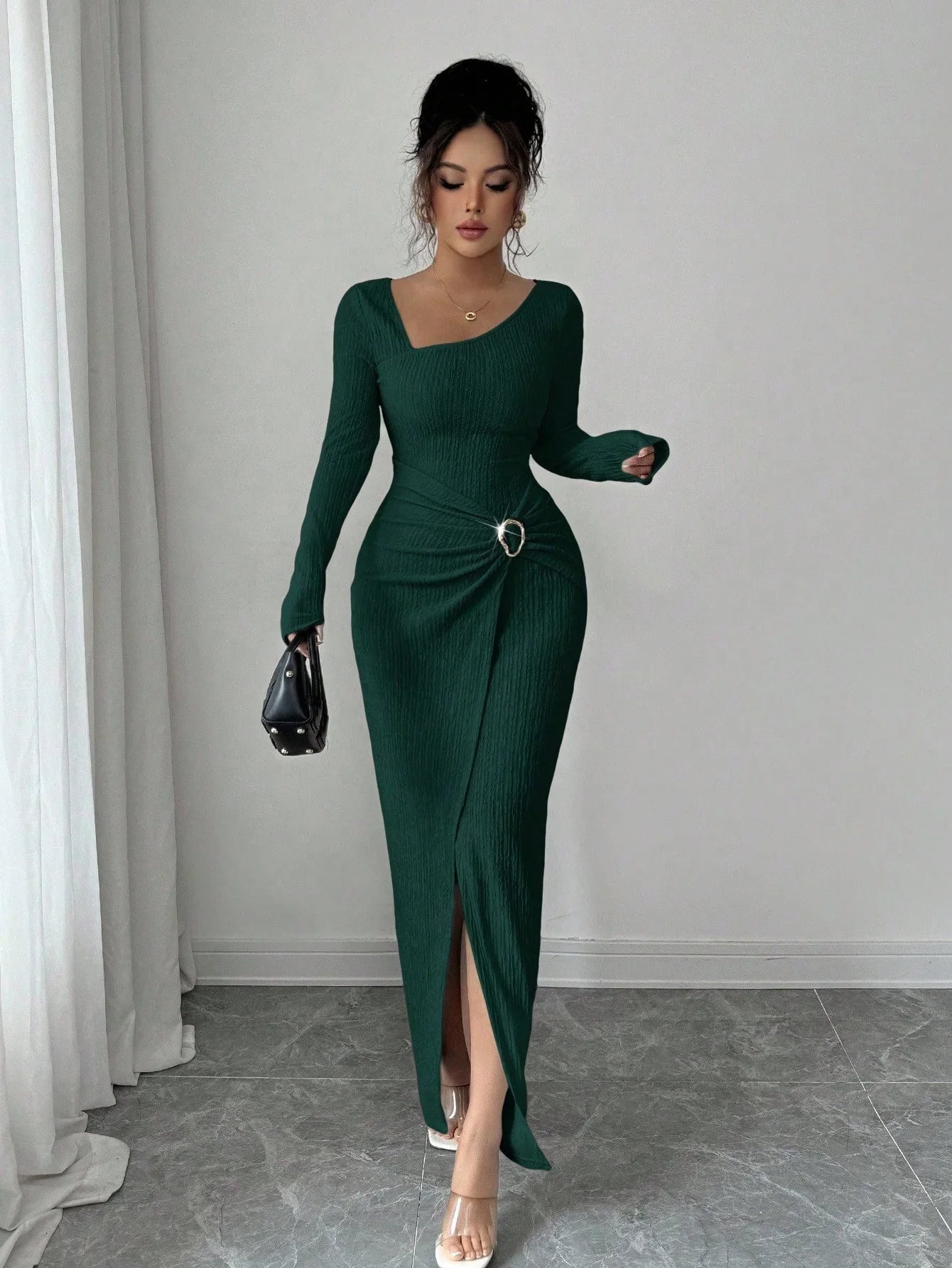 Woman in fitted dark green ribbed knit long-sleeve dress with side slit and silver buckle detail