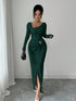 Woman in fitted dark green ribbed knit long-sleeve dress with side slit and silver buckle detail