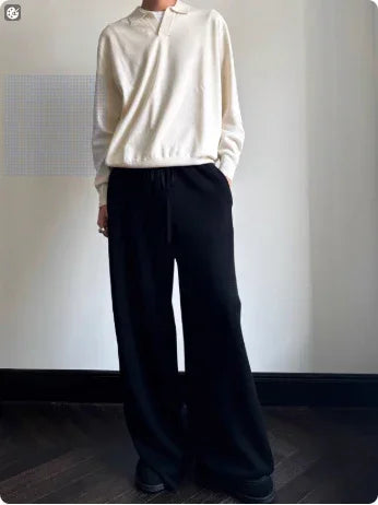 Person wearing a loose cream long-sleeve shirt and black wide-leg pants, relaxed fit.