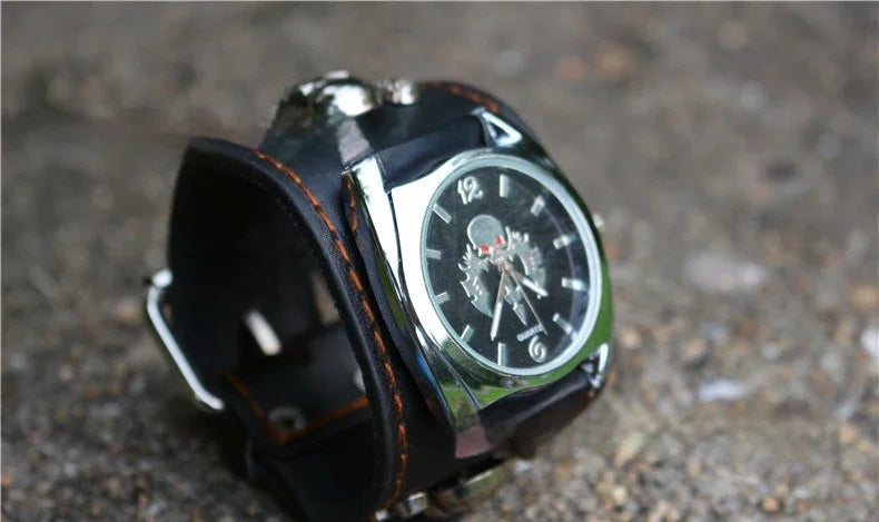 Black leather wide cuff watch with silver accents and a skeleton dial on a textured surface