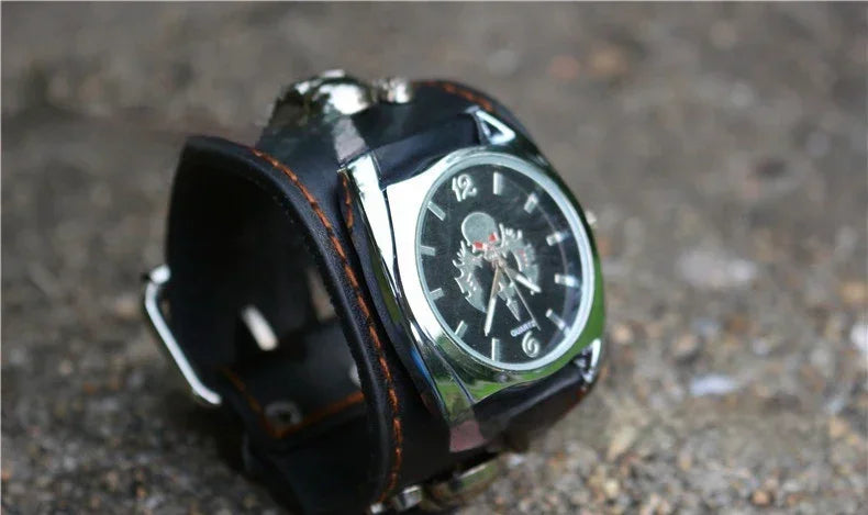 Black leather wide cuff watch with silver accents and a skeleton dial on a textured surface