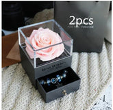 Gift box with a pink artificial rose and black drawer displaying blue beaded bracelets