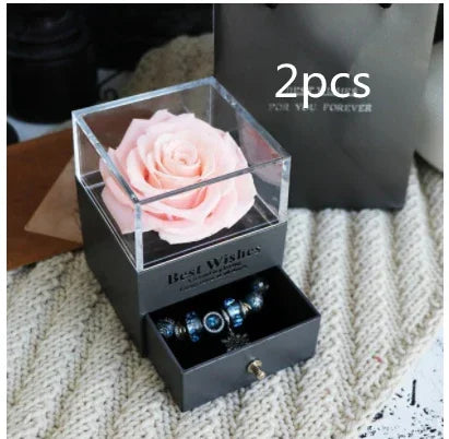 Gift box with a pink artificial rose and black drawer displaying blue beaded bracelets