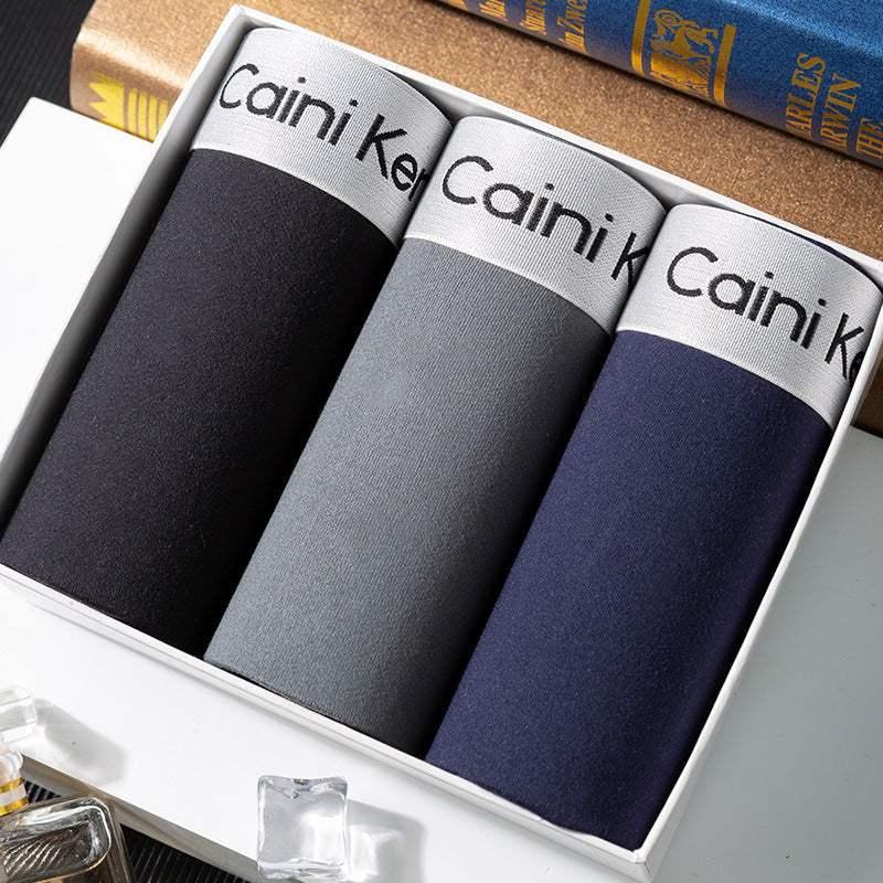 Three pairs of men's boxer briefs in black, gray, and navy with elastic waistband, neatly boxed