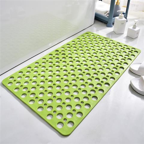Green non-slip rubber bath mat with circular holes on white bathroom floor