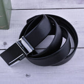 Black leather belt with sleek metal buckle, modern streetwear accessory on wood background