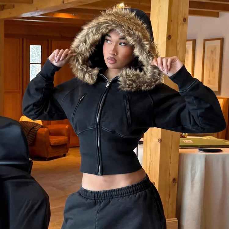 Woman wearing black cropped zip-up hoodie with faux fur hood and relaxed fit joggers indoors