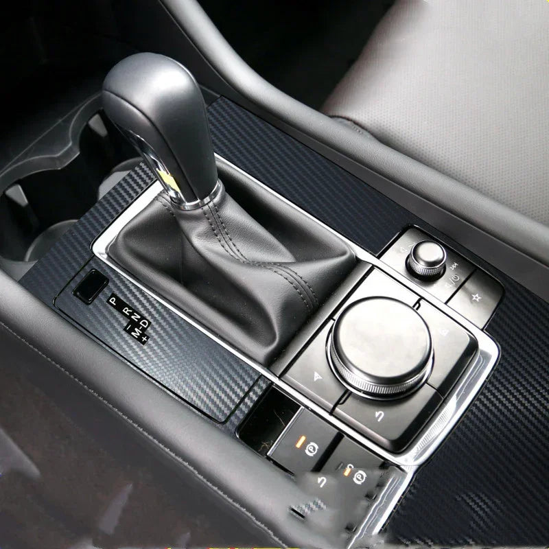 Close-up of a car's black leather gear shift with carbon fiber trim and control knob