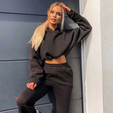 Woman in black cropped hoodie and joggers, relaxed streetwear style, soft fabric, loose fit.
