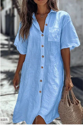 Woman wearing loose fit light blue button-up linen shirt dress with short sleeves