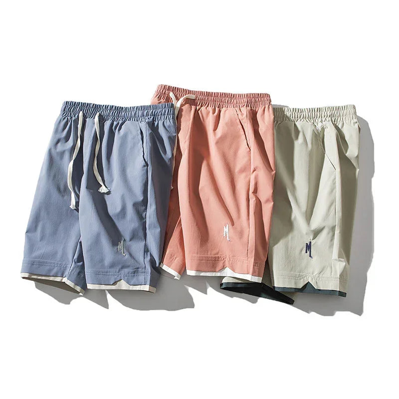 Three relaxed fit drawstring shorts in blue, peach, and beige with embroidered detailing.