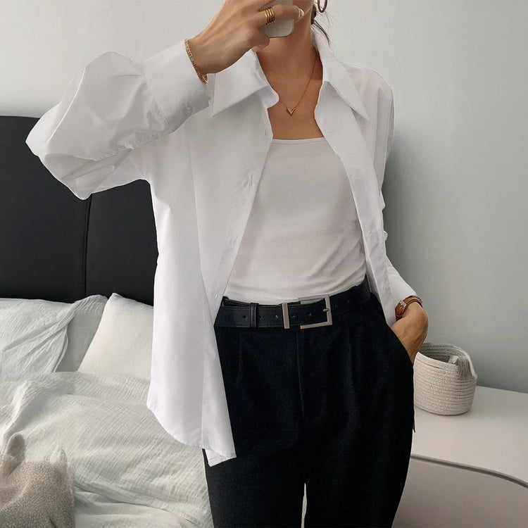 Woman in relaxed fit white cotton button-up shirt, white tank top, and black trousers