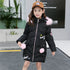 Girl in a long black puffer coat with pink faux fur trim and pom poms, casual street style