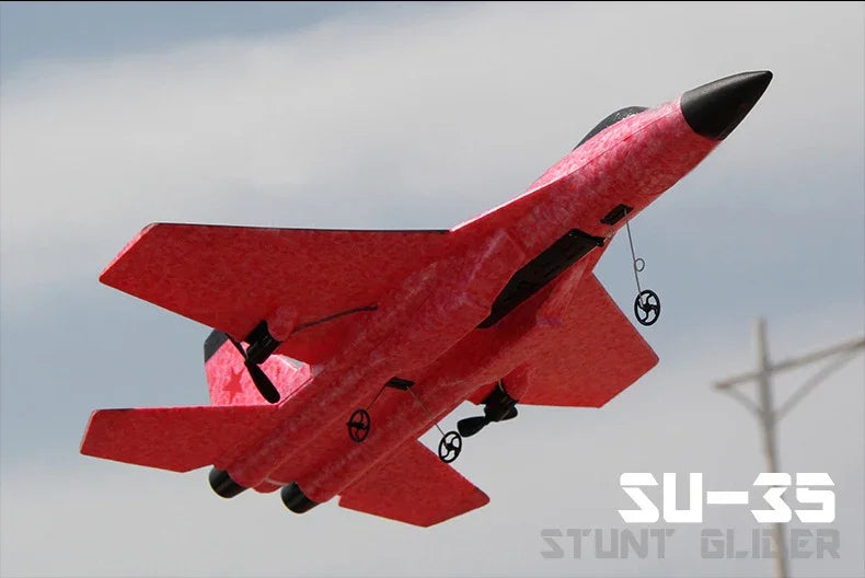 Red foam stunt glider jet toy with black accents, lightweight design, flying outdoors in sky.
