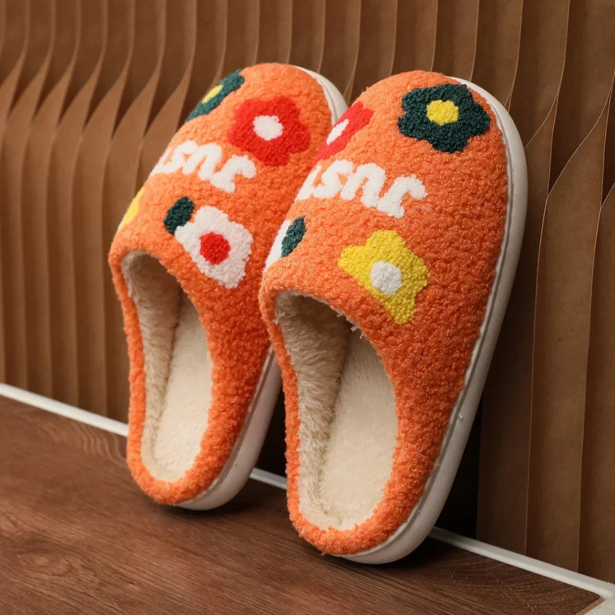 Orange fuzzy slippers with colorful flower patterns and soft plush lining, cozy fit