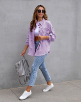 Woman in oversized lavender denim jacket, white crop top, ripped skinny jeans, and white sneakers