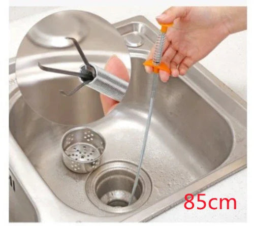 Flexible stainless steel drain clog remover tool with orange handle in kitchen sink, 85cm long