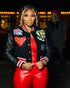 Woman wearing black varsity jacket with patches and red faux leather crop top and pants