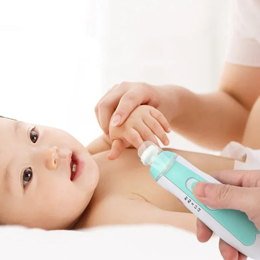 Baby lying on white bed wearing no clothing, adult trimming baby's nails with an electric nail trimmer