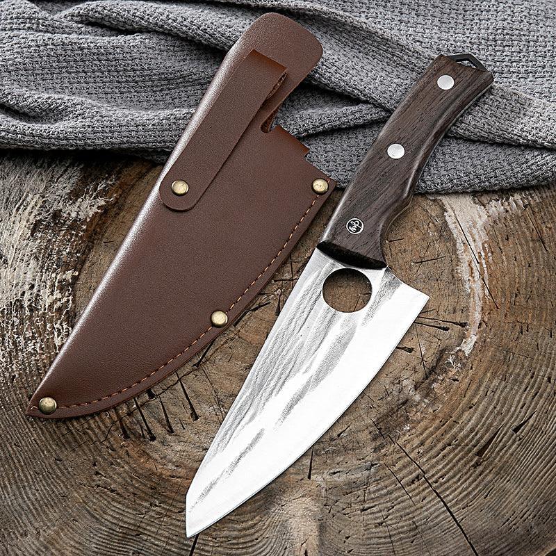 Hand-forged chef knife with rustic wooden handle and leather sheath on wooden surface