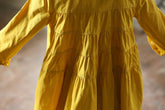 Yellow long-sleeve tiered cotton dress with loose fit and gathered detailing