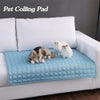 Blue quilted pet cooling pad on white sofa with dogs resting