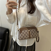 Woman in loose white satin blouse with embroidery, wearing brown checkered crossbody bag