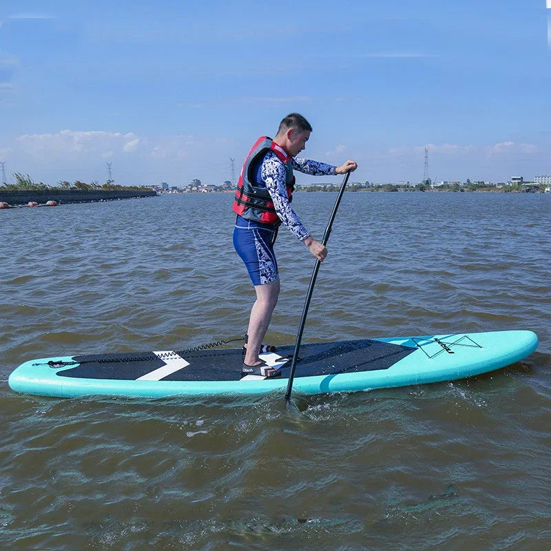 Man paddleboarding wearing blue patterned athletic shirt, blue shorts, and red life vest