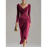 Woman wearing a deep pink velvet midi dress with long sleeves and draped cowl neckline