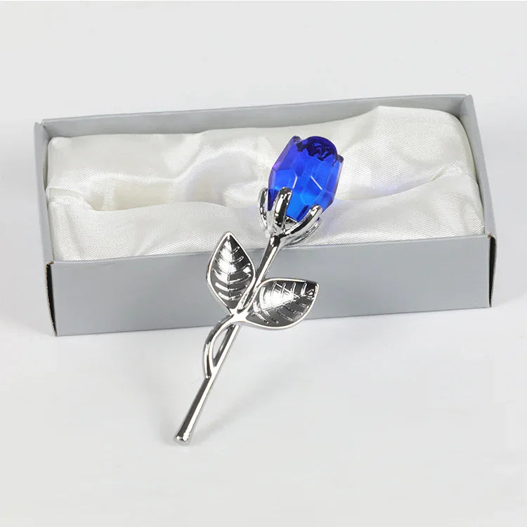 Silver metal rose with blue crystal flower in a gift box on white satin fabric
