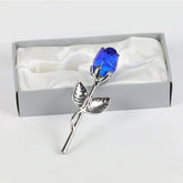 Silver metal rose with blue crystal flower in a gift box on white satin fabric