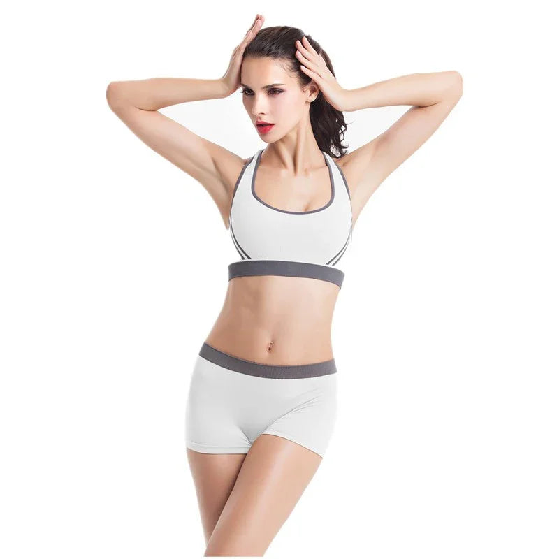Woman wearing white athletic sports bra and shorts with gray trim, fitted and seamless style