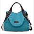 Teal canvas tote bag with black faux leather straps and zippered front pocket