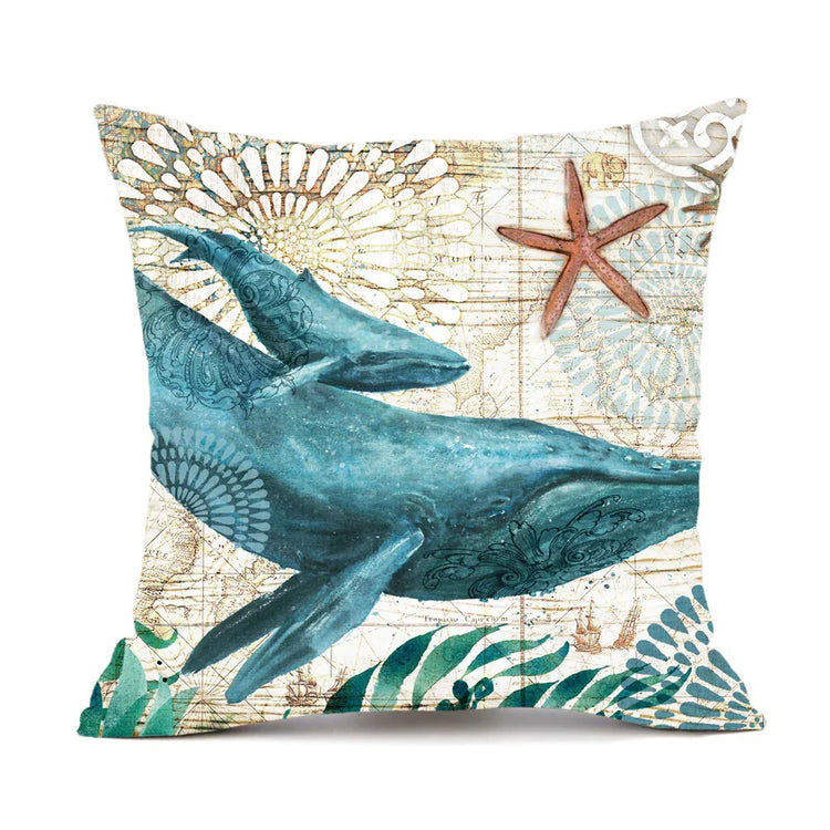 Decorative pillow with blue whale and starfish print on beige, nautical patterned fabric.