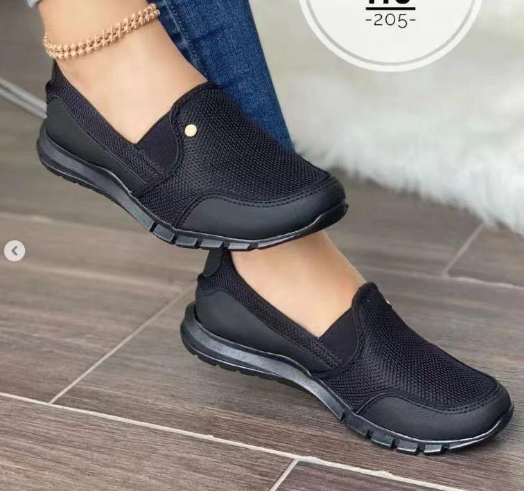 Black mesh slip-on sneakers with cushioned sole, worn with blue jeans, modern streetwear style