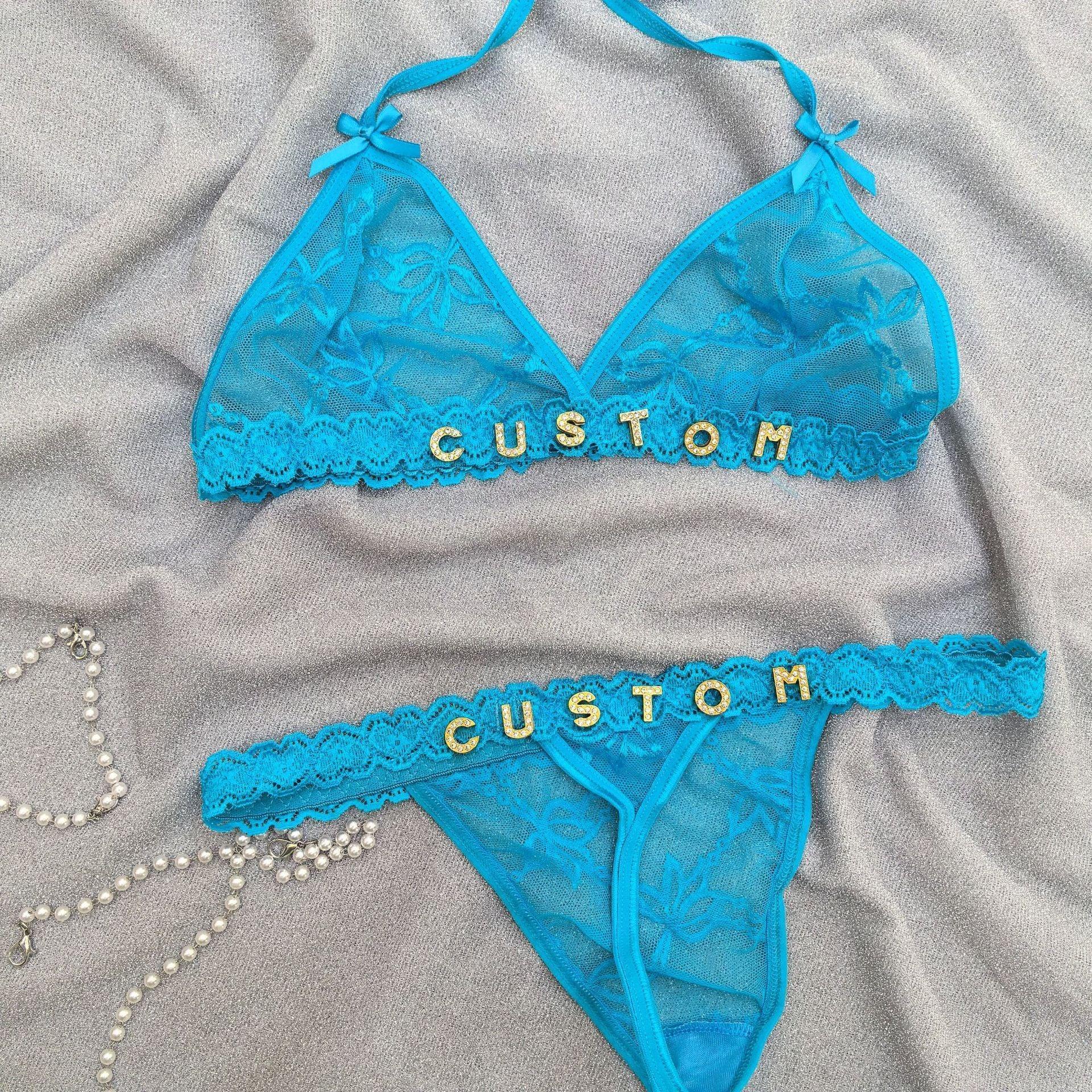 Blue lace bralette and thong set with floral mesh, gold custom letter detail, laid on fabric