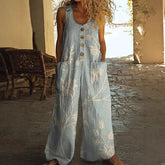 Woman wearing loose light blue linen jumpsuit with floral print, buttons, and large pockets
