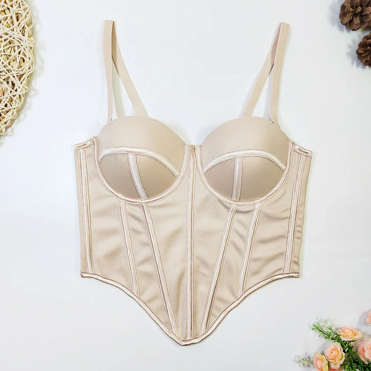 Beige satin corset top with structured boning, molded cups, and adjustable straps, laid flat.