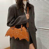 Oversized dark grey blazer with loose fit, paired with brown bat wing handbag featuring stitched web design.