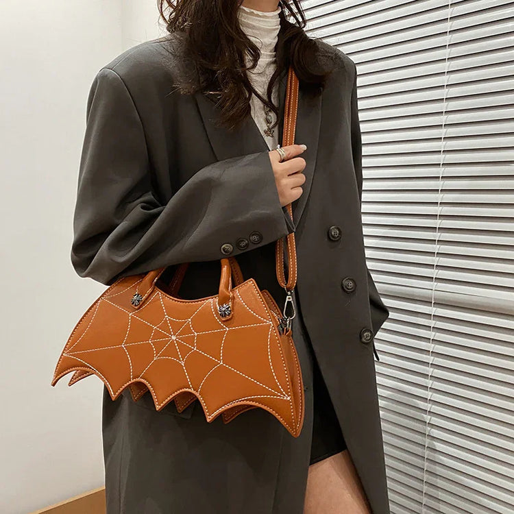 Oversized dark grey blazer with loose fit, paired with brown bat wing handbag featuring stitched web design.