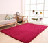 Modern living room with plush red area rug, light sofa, and natural wood furniture