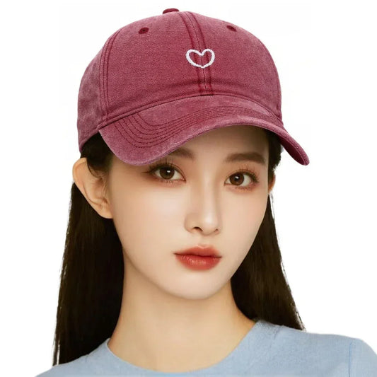 Woman wearing a burgundy cotton baseball cap with embroidered heart and relaxed fit