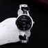 Silver quartz wristwatch with black dial, crystal heart accents, and metal bracelet strap