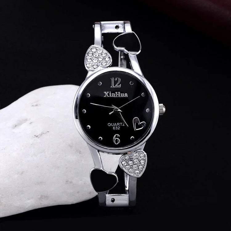 Silver quartz wristwatch with black dial, crystal heart accents, and metal bracelet strap