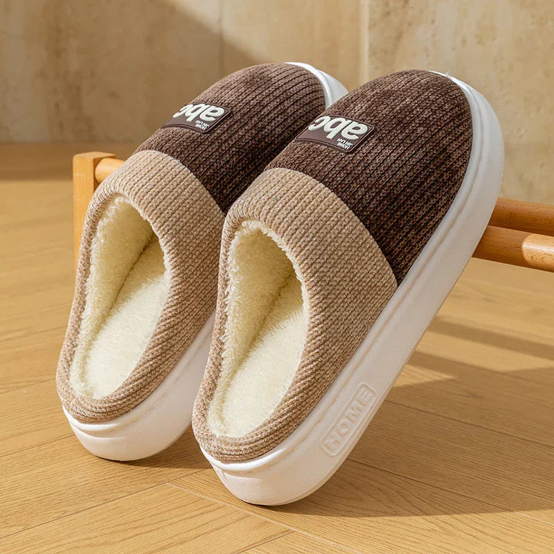 Brown and beige ribbed slip-on slippers with plush lining and thick white soles on wooden floor