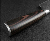 Close-up of a polished dark wood knife handle with metal accents on a textured surface