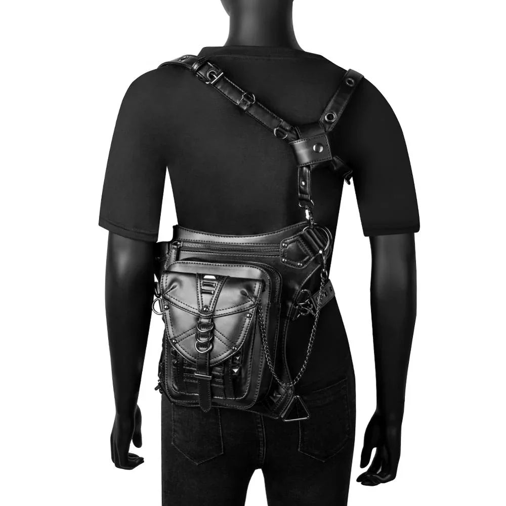 Mannequin wearing black short sleeve t-shirt, fitted jeans, and a faux leather utility chest bag with chain and buckle details.
